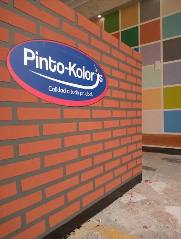 Proceso de producción y sedes de Pinto Kolors — letrero logo muro ladrillo